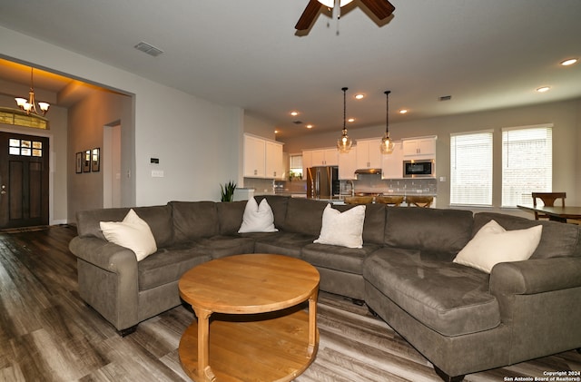 living room with dark wood-type flooring, sink, and ceiling fan with notable chandelier