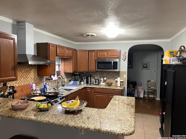 kitchen with crown molding, light stone countertops, sink, wall chimney exhaust hood, and kitchen peninsula