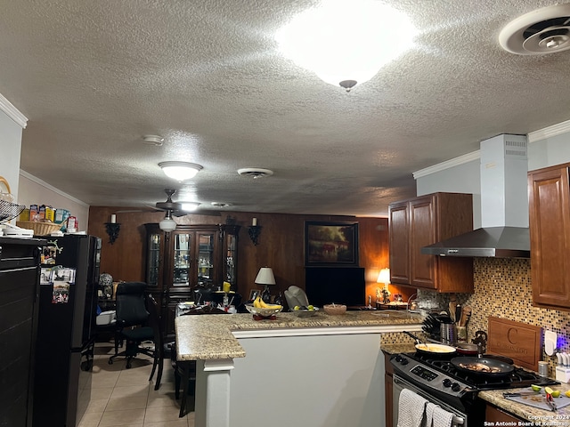 kitchen featuring crown molding, wall chimney exhaust hood, a textured ceiling, and gas range