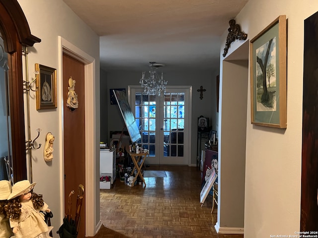 corridor featuring an inviting chandelier, dark parquet flooring, and french doors