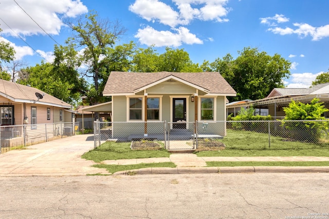 view of front of property with a fenced front yard, driveway, a carport, and a shingled roof