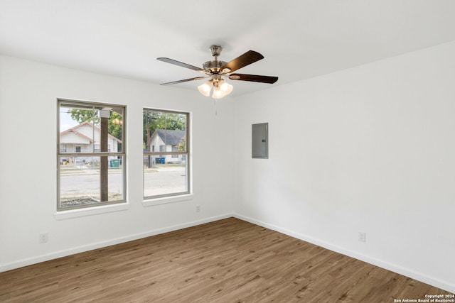 spare room featuring a ceiling fan, wood finished floors, electric panel, and baseboards