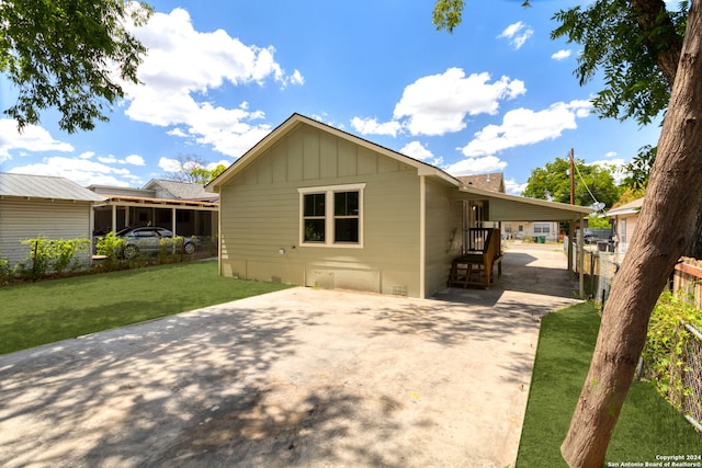 view of home's exterior with board and batten siding, driveway, fence, and a lawn