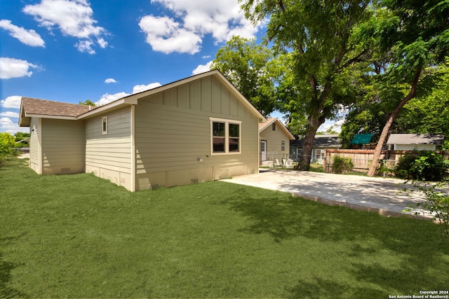 rear view of property featuring a lawn and a patio