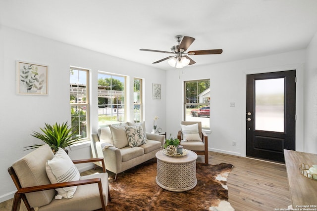 living area with a wealth of natural light, ceiling fan, baseboards, and wood finished floors