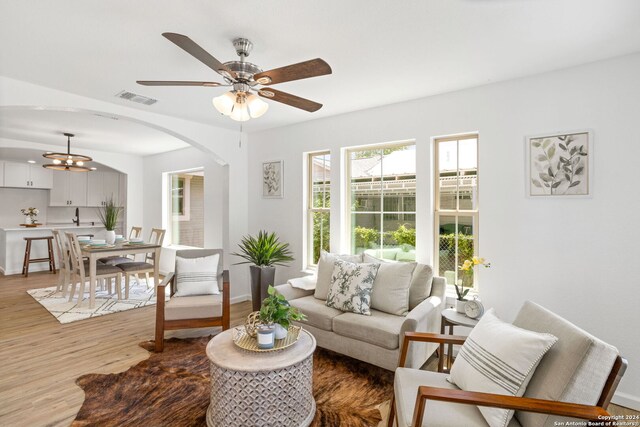 living room with ceiling fan with notable chandelier and hardwood / wood-style flooring