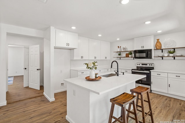 kitchen with stainless steel range with electric stovetop, light hardwood / wood-style flooring, an island with sink, sink, and white cabinets