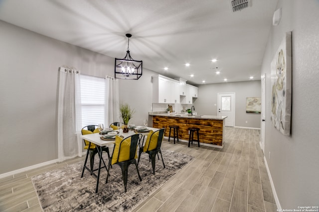 dining room with light wood-type flooring and a notable chandelier