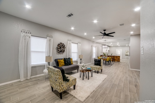 living room with light hardwood / wood-style flooring and ceiling fan with notable chandelier