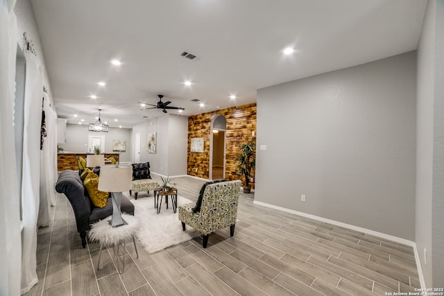 living room featuring light wood-type flooring and ceiling fan with notable chandelier