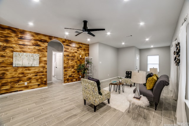 living area featuring ceiling fan, wooden walls, and light hardwood / wood-style floors