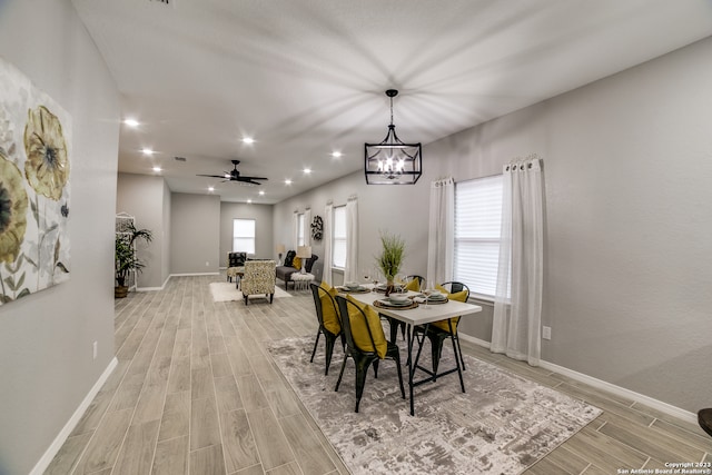 dining area featuring ceiling fan with notable chandelier, light wood-type flooring, and a healthy amount of sunlight