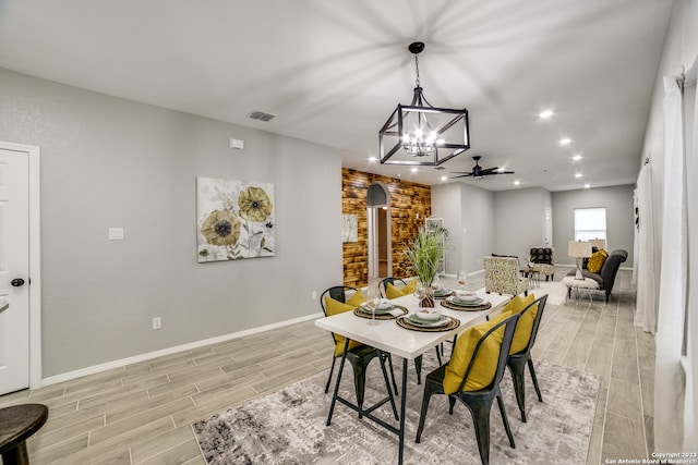 dining space featuring ceiling fan with notable chandelier and light hardwood / wood-style floors