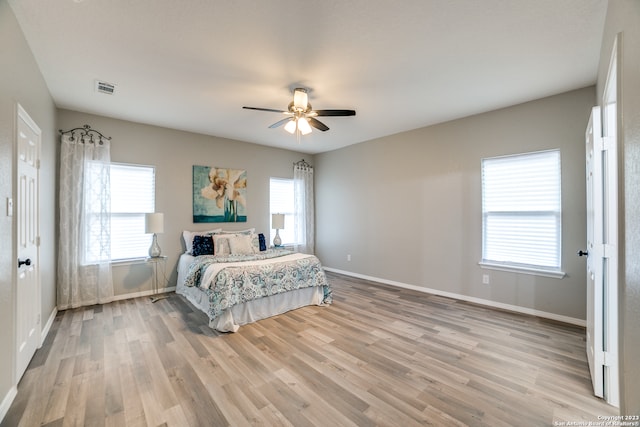 bedroom with multiple windows, ceiling fan, and light hardwood / wood-style floors