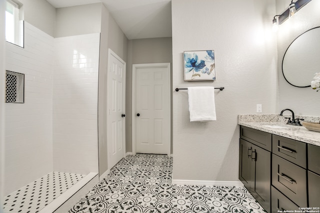 bathroom with tiled shower, vanity, and tile patterned flooring