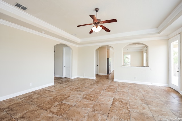 empty room featuring a tray ceiling, ceiling fan, and ornamental molding