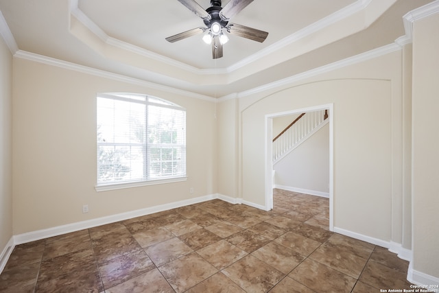 spare room with a raised ceiling, ceiling fan, and ornamental molding