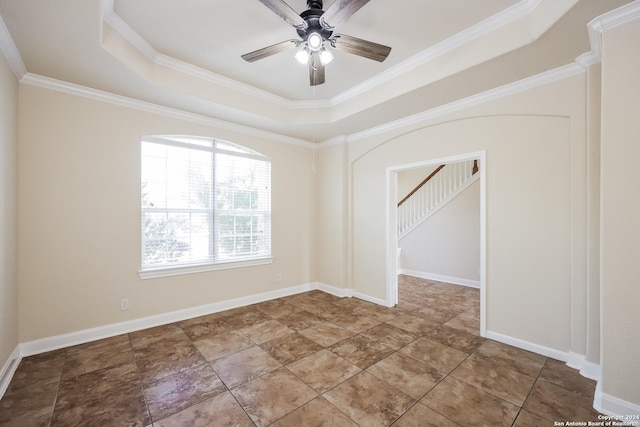 spare room with ceiling fan, crown molding, a raised ceiling, and baseboards