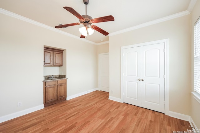 empty room with a ceiling fan, crown molding, light wood-style floors, and baseboards