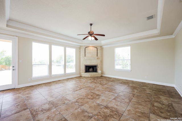 unfurnished living room featuring a wealth of natural light, a raised ceiling, ceiling fan, and a fireplace