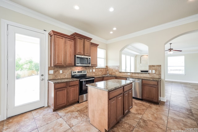 kitchen with a healthy amount of sunlight, ceiling fan, a center island, and appliances with stainless steel finishes