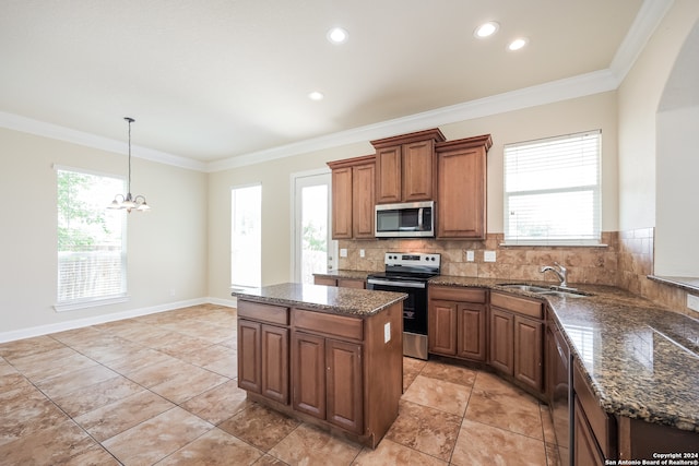 kitchen featuring appliances with stainless steel finishes, a center island, sink, decorative backsplash, and a chandelier