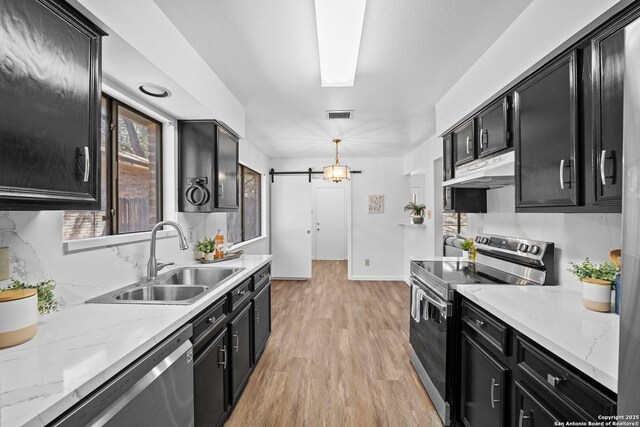 kitchen with light wood-type flooring, tasteful backsplash, stainless steel appliances, and a notable chandelier