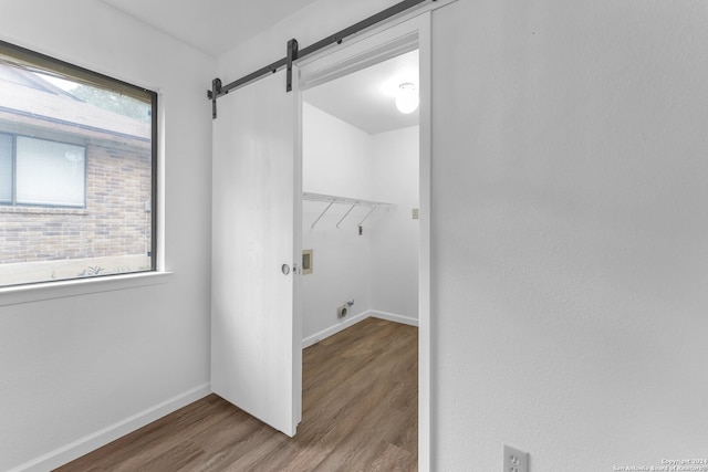 clothes washing area with washer hookup, hardwood / wood-style flooring, a barn door, and hookup for an electric dryer