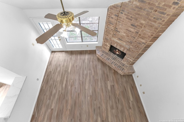 unfurnished living room featuring ceiling fan, a fireplace, and dark hardwood / wood-style flooring