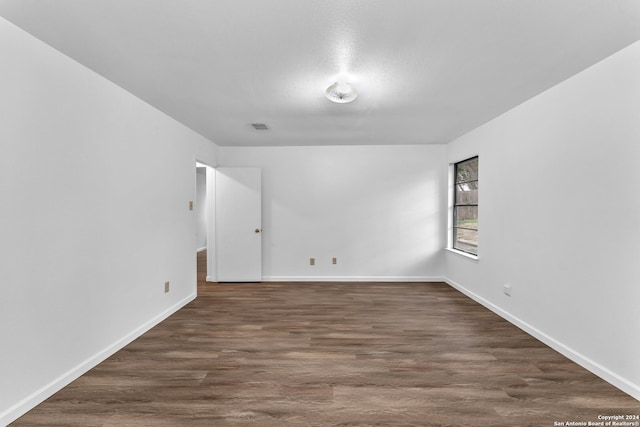 spare room featuring dark wood-type flooring and a textured ceiling