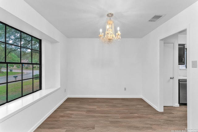 unfurnished dining area featuring hardwood / wood-style floors, a wealth of natural light, and a notable chandelier