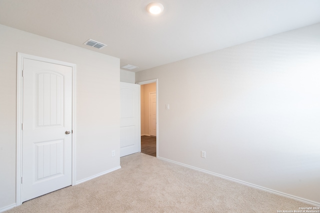 unfurnished bedroom with light colored carpet and a closet