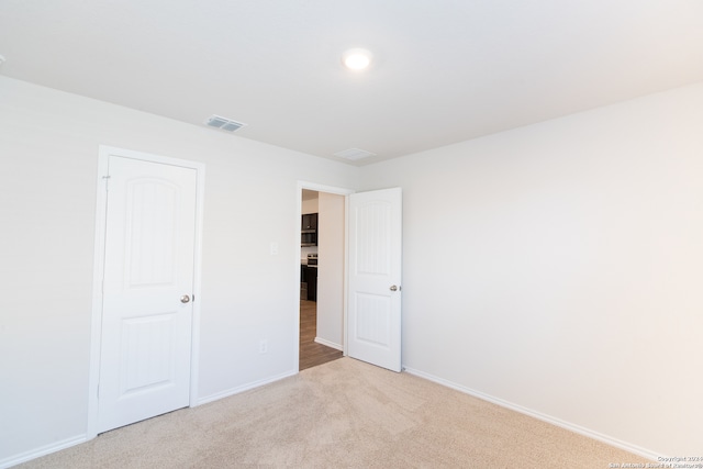 unfurnished bedroom with light colored carpet and a closet