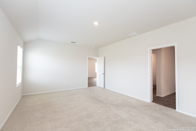 carpeted empty room featuring lofted ceiling