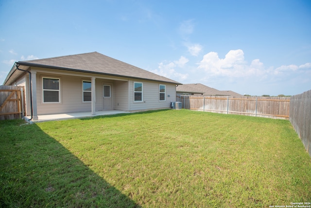 rear view of house with central air condition unit, a yard, and a patio area