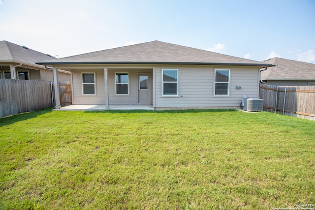 rear view of house with central AC unit, a patio, and a lawn