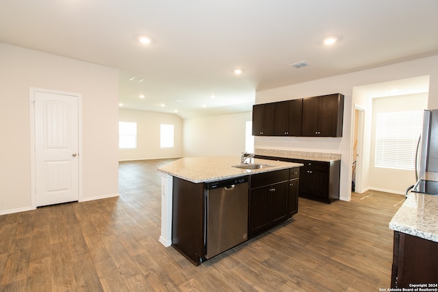 kitchen with dark brown cabinets, stainless steel appliances, light stone counters, a center island with sink, and light hardwood / wood-style floors