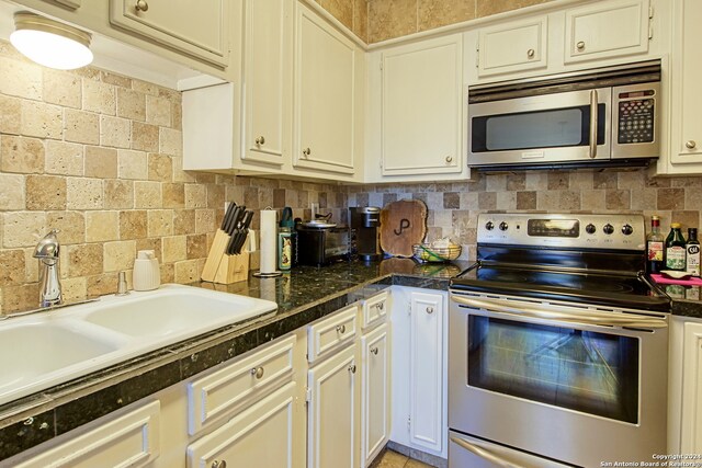 kitchen featuring white cabinets, appliances with stainless steel finishes, backsplash, and sink