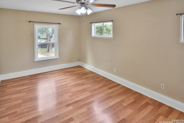 empty room with ceiling fan, plenty of natural light, and light hardwood / wood-style flooring