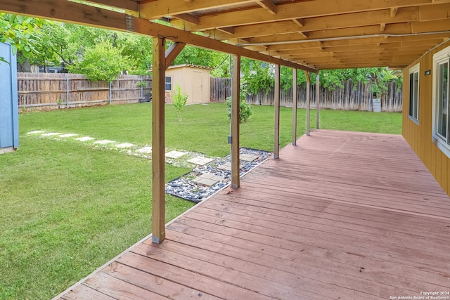 wooden terrace featuring a lawn and a storage shed