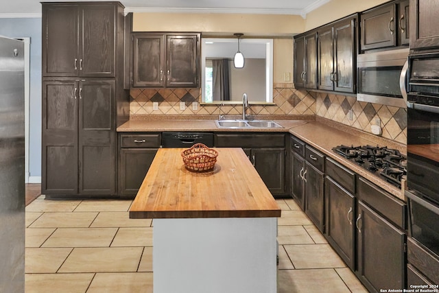 kitchen with hanging light fixtures, appliances with stainless steel finishes, sink, light tile patterned flooring, and butcher block counters