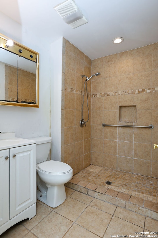 bathroom with toilet, a tile shower, and vanity