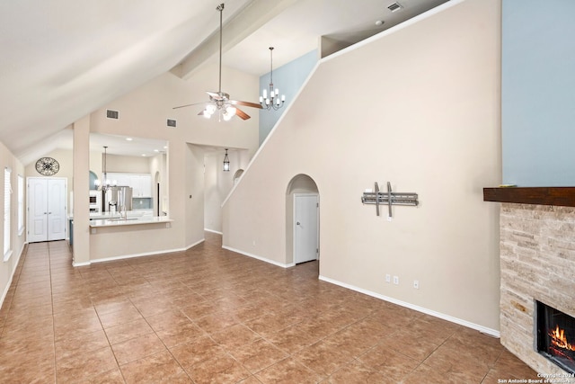 unfurnished living room with tile patterned floors, ceiling fan with notable chandelier, beamed ceiling, a stone fireplace, and high vaulted ceiling