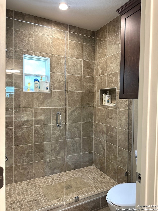 bathroom featuring toilet and a shower with shower door