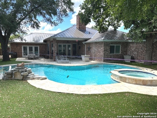 view of swimming pool with a yard, french doors, a patio, and an in ground hot tub