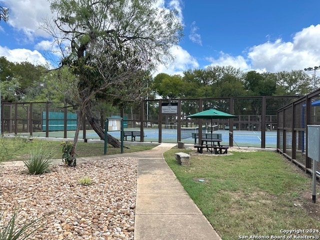 surrounding community featuring tennis court and a lawn