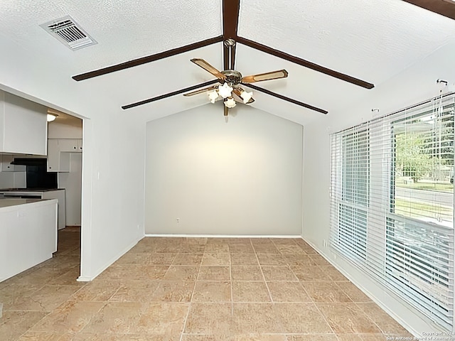 unfurnished room featuring a textured ceiling, ceiling fan, and lofted ceiling with beams