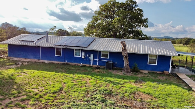 back of house with a yard, solar panels, and central air condition unit