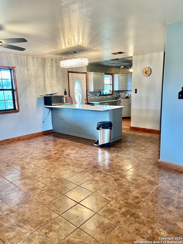 kitchen featuring a kitchen bar, kitchen peninsula, ceiling fan, and tasteful backsplash