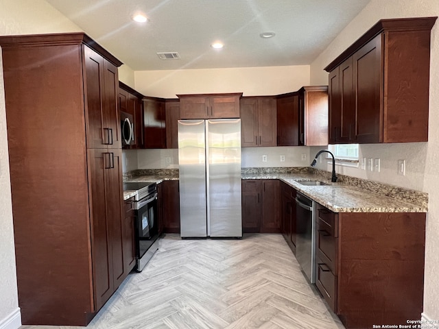 kitchen featuring light parquet floors, sink, light stone countertops, and appliances with stainless steel finishes